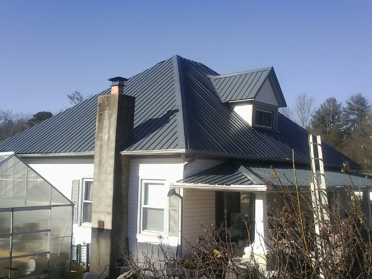 Dark blue standing seam metal roof on a white farmhouse with dormer — Slate & Tile Roof Repair by Roofing Brothers in Sumas