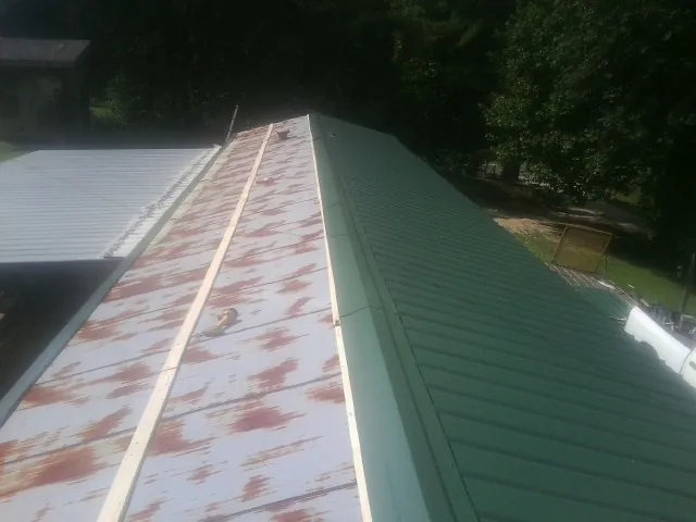 Old rusted panels beside newly installed green metal roofing — Wind Damage Roof Repair by Roofing Brothers in Sumas