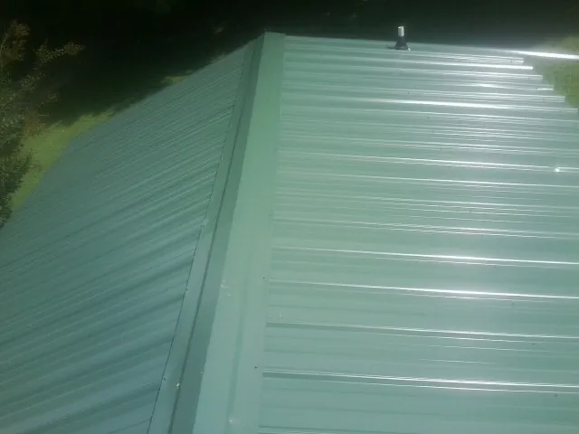 New green metal panels meeting at the ridge of a roof — Flat Roof Repair work by our crew in Sumas