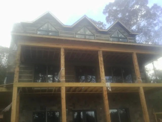 Dormers and porch framing on a large log home under construction — Roof Coating work by our crew in Sumas