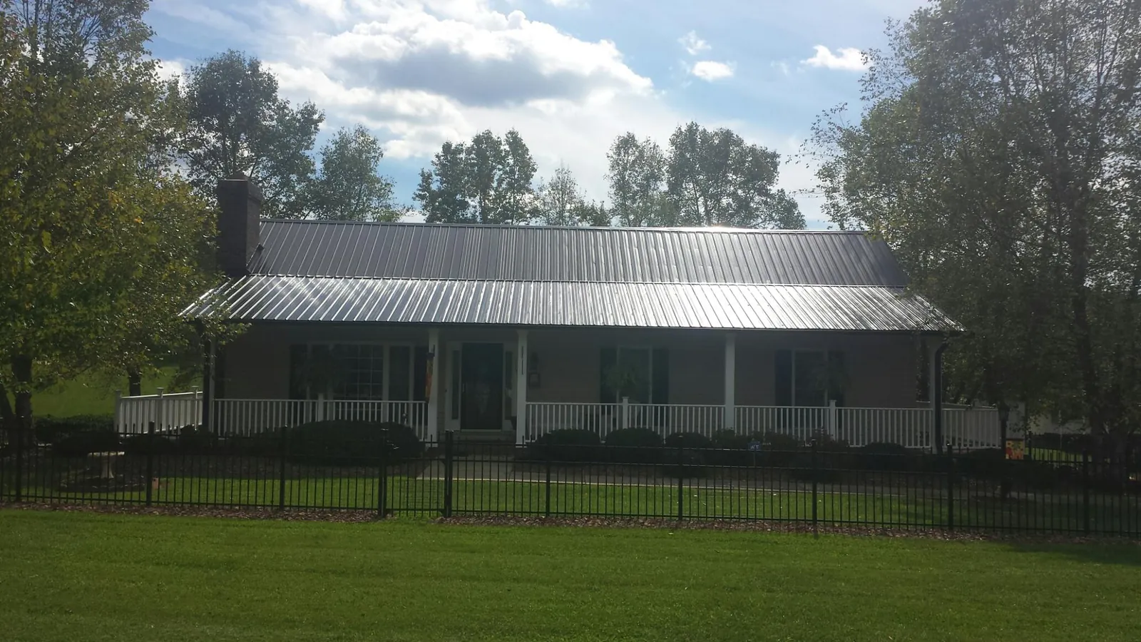 Gray metal roof on a brick ranch with a full width front porch — Gutter Guard Installation work by our crew in Sumas