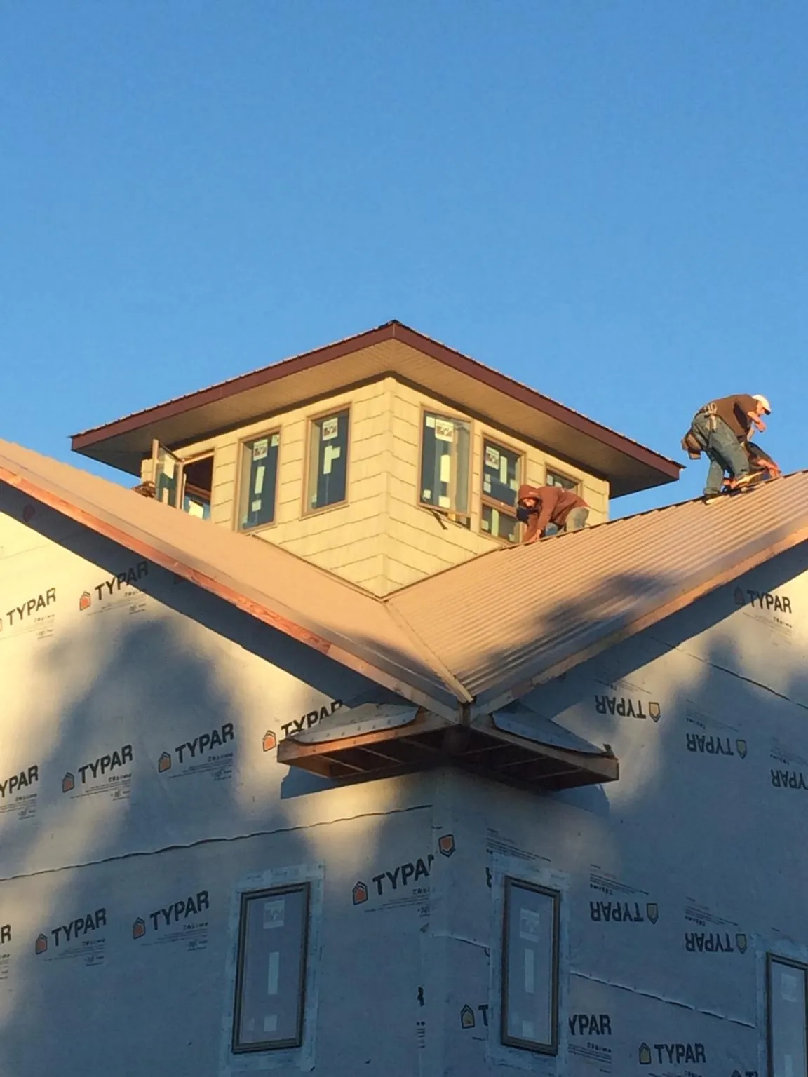 Roofers working around a rooftop cupola on a new metal roof at sunset — Roof Waterproofing in Sumas by Roofing Brothers